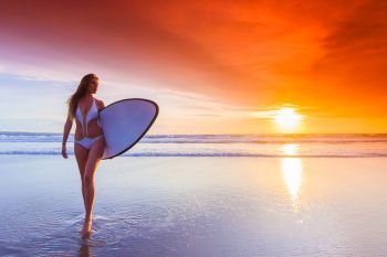 Surfer woman on beach at sunset. Beautiful surfer woman on the beach at sunset