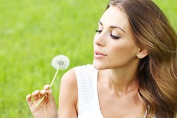 beautiful young woman with dandelion lying on grass. beautiful young woman with dandelion. beautiful young woman with dandelion