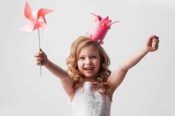 Princess girl with pinwheel. Beautiful little candy princess girl in crown holding pinwheel and smiling