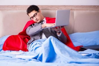 Superhero businessman working from his bed