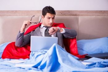Superhero businessman working from his bed