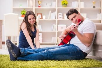 Romantic pair playing guitar on floor
