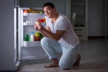 Man at the fridge eating at night