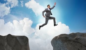 Ambitious businessman jumping over the cliff