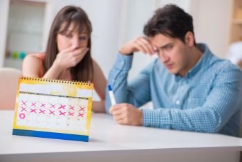 Young family in pregnancy planning concept with ovulation calendar