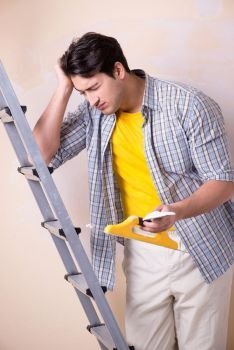 Young man applying plaster on wall at home