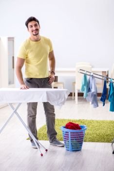 Handsome man husband doing clothing ironing at home