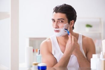 The young handsome man shaving early in the morning at home. Young handsome man shaving early in the morning at home. The young handsome man shaving early in the morning at home