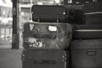 Old vintage suitcases stacked on train railway platform in sepia finish