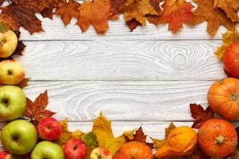 Autumn leaves, apples and pumpkins over old wooden background with copy space