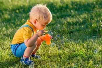 Portrait of toddler child outdoors. Rural scene with one year old baby boy blowing soap bubbles. Healthy preschool children summer activity. Kid playing outside. 