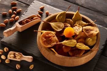 Dried fruits and nuts on slate plate over vintage rustic wooden background 