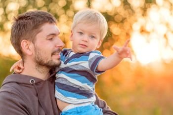 Happy man and his child having fun outdoors. Family lifestyle rural scene of father and son in sunset sunlight. 