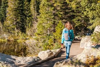 Woman tourist walking on trail near Bear Lake at autumn in Rocky Mountain National Park. Colorado, USA. 