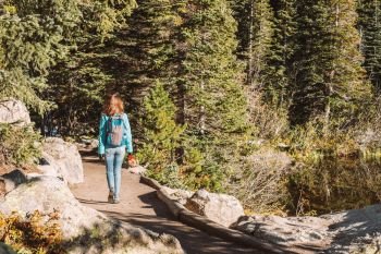 Tourist on trail near Bear Lake in Colorado. Woman tourist walking on trail near Bear Lake at autumn in Rocky Mountain National Park. Colorado, USA. 