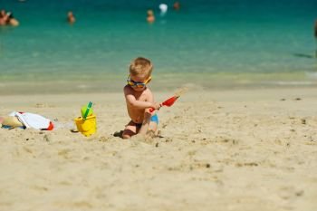 Toddler boy playing with shovel and sand on beach . Two year old toddler boy playing with shovel and sand on beach 