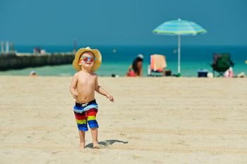 Two year old toddler boy running on beach . Two year old toddler boy in sun hat running on beach 