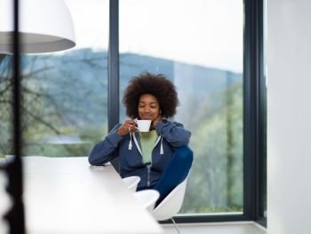Handsome young african american woman drinking coffee and using a mobile phone at  home