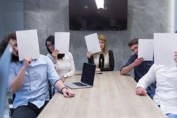Portrait of a young business team holding a white paper over their face  in the startup office