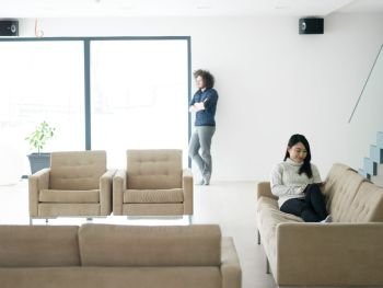 Young multiethnic couple relaxing at luxury home with tablet computers reading in the living room on the sofa couch.