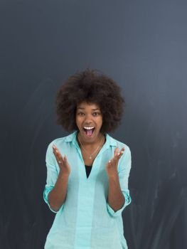 portrait of a beautiful friendly African American woman with a curly afro hairstyle and lovely smile in front of gray chalkboard