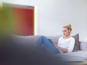 young happy woman on sofa using tablet computer at luxury home