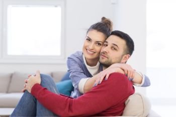 Happy young couple hugging and relaxing on sofa at home