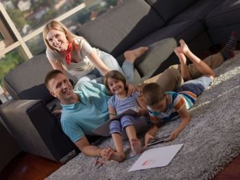 Happy Young Family Playing Together at home using a tablet and a children’s drawing set