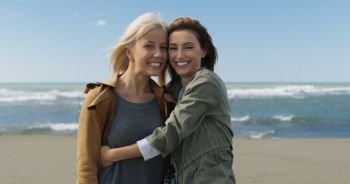 two cute young women smiling and enjoying life on an autumn walk along the ocean