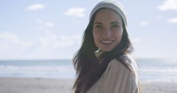 Portrait Of A Young Woman In Autumn Clothes Smiling On The Beach