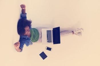 Portrait of happy young african american woman sitting on floor with laptop top view