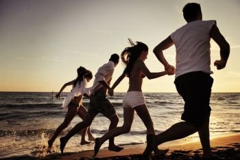 happy young people group have fun white running and jumping on beacz at sunset time
