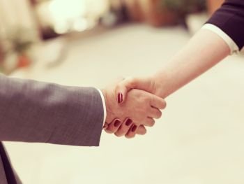 business partners concept with businessman and businesswoman handshake at modern office indoors