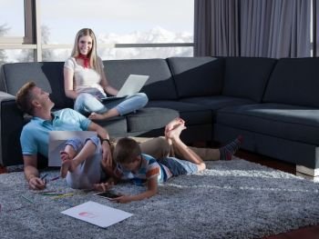 Happy Young Family Playing Together at home on the floor using a laptop computer and a children’s drawing set