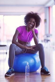 happy african american woman with a curly afro hairstyle in a  gym relaxing after pilates workout. woman  relaxing after pilates workout