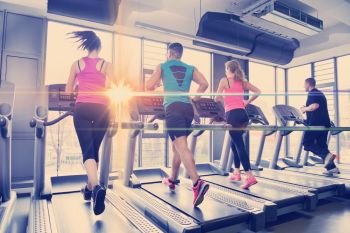 group of young people running on treadmills in modern sport  gym. Group of people running on treadmills