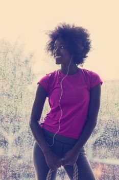 portrait of young afro american woman in gym on workout break while listening music on earphone  and dancing  rainy day and bad weather outdooor. portrait of young afro american woman in gym while listening mus