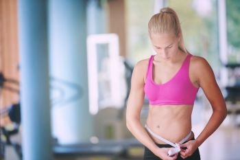 young fit woman measuring belly on a training  in  fitness gym. young fit woman measuring belly