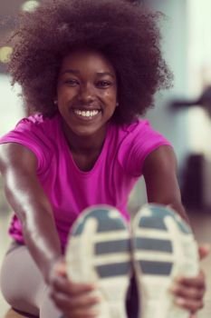 happy young african american woman in a gym stretching and warming up before workout. woman in a gym stretching and warming up before workout