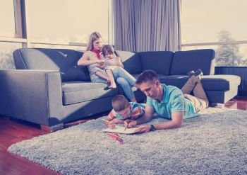Happy Young Family Playing Together at home on the floor using a tablet and a children’s drawing set. young couple spending time with kids