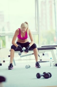 halethy young woman exercise with dumbells and relaxing on banch in fitness gym. young woman exercise with dumbells