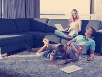 Happy Young Family Playing Together at home on the floor using a laptop computer and a children’s drawing set. young couple spending time with kids at home