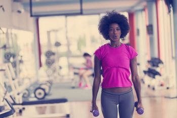 happy healthy african american woman working out in a crossfit gym on weight loss with dumbbells. woman working out in a crossfit gym with dumbbells