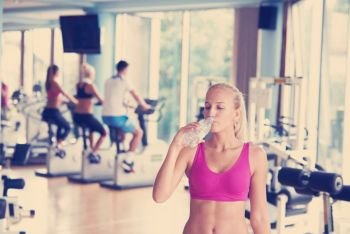 young healthy blonde woman in fitness gym drink water. woman in fitness gym drink water