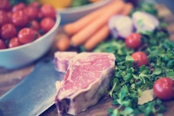 Juicy slice of raw steak  with vegetables around on a wooden table. Juicy slice of raw steak on wooden table