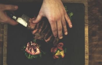 top view of Chef hands in hotel or restaurant kitchen serving beef steak with vegetable decoration. top view of Chef hands serving beef steak