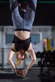 athlete woman doing abs exercises hanging upside down on horizontal bar at crossfitness gym. woman doing abs exercises