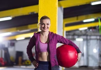 Portrait of beautiful athlete woman with red medicine  ball at crossfitness gym. portrait of woman with red crossfitness ball
