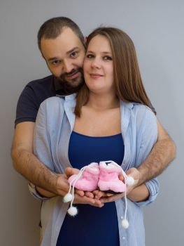 pregnant couple holding newborn baby shoes. young  pregnant couple holding newborn baby shoes isolated on white background in family and parenthood concept
