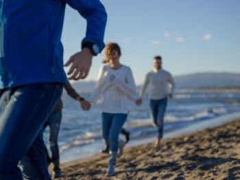 group of young friends spending day together running on the beach during autumn day. Group of friends running on beach during autumn day